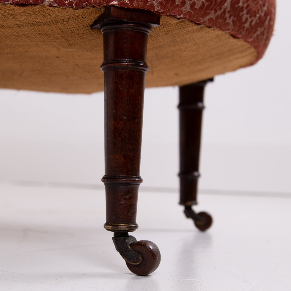 A pair of 19th-century Victorian tub armchairs upholstered in patterned red fabric with turned wooden legs on brass castors. View V