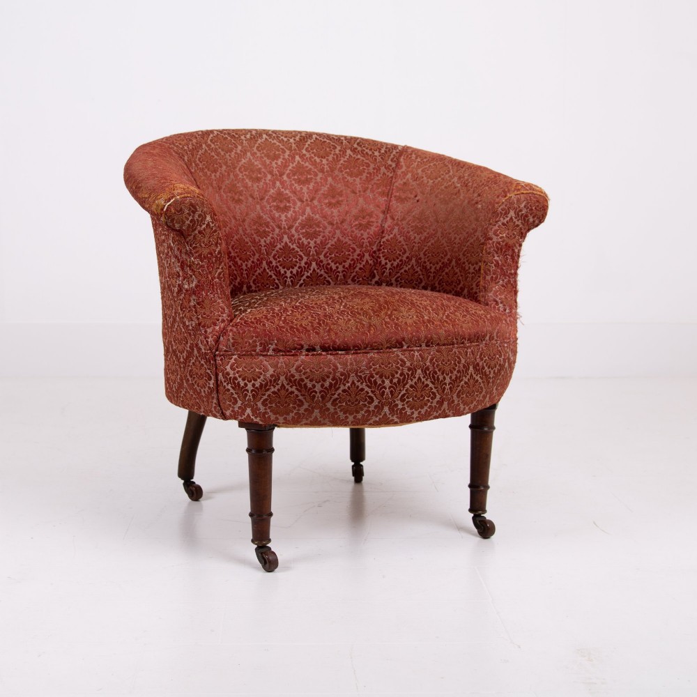 A pair of 19th-century Victorian tub armchairs upholstered in patterned red fabric with turned wooden legs on brass castors. View X