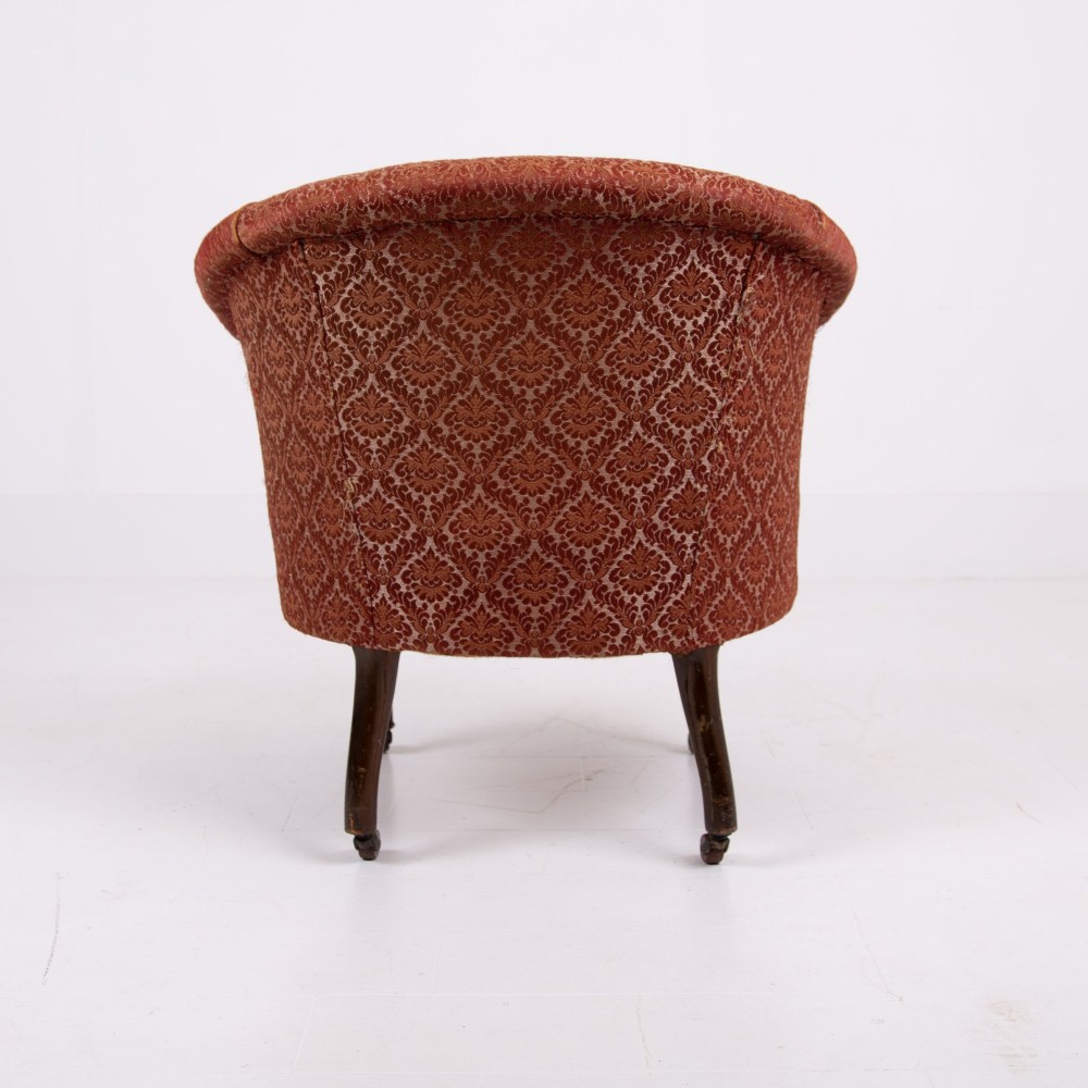 A pair of 19th-century Victorian tub armchairs upholstered in patterned red fabric with turned wooden legs on brass castors. View XI