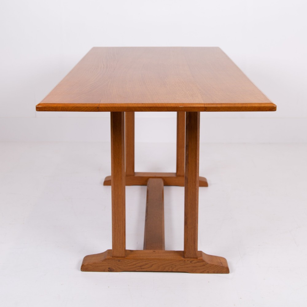 A 1930s Heals oak dining table featuring a rectangular solid timber top supported by a double-upright trestle base. View X