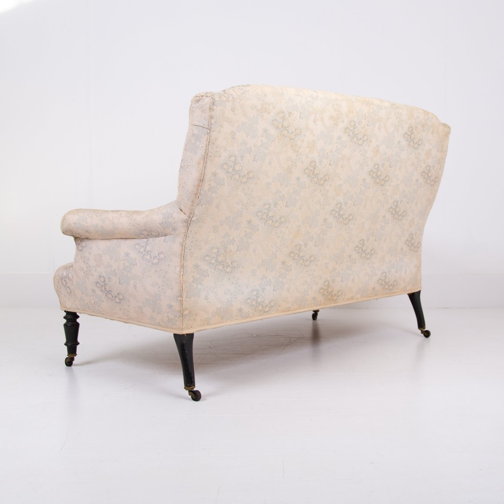 An antique French Napoleon III sofa upholstered in pale cream patterned fabric with deep buttoning, curved backrest, and turned dark wooden legs on brass castors. View XI