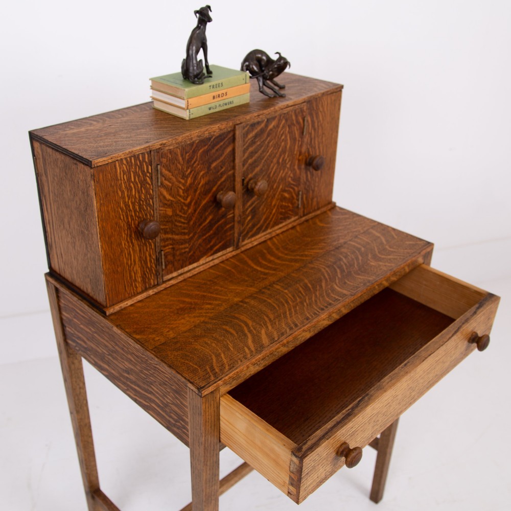 A 1930s warm brown oak writing desk featuring a top compartment with cupboard doors, side fold-out sections, and a single drawer on square legs. View III