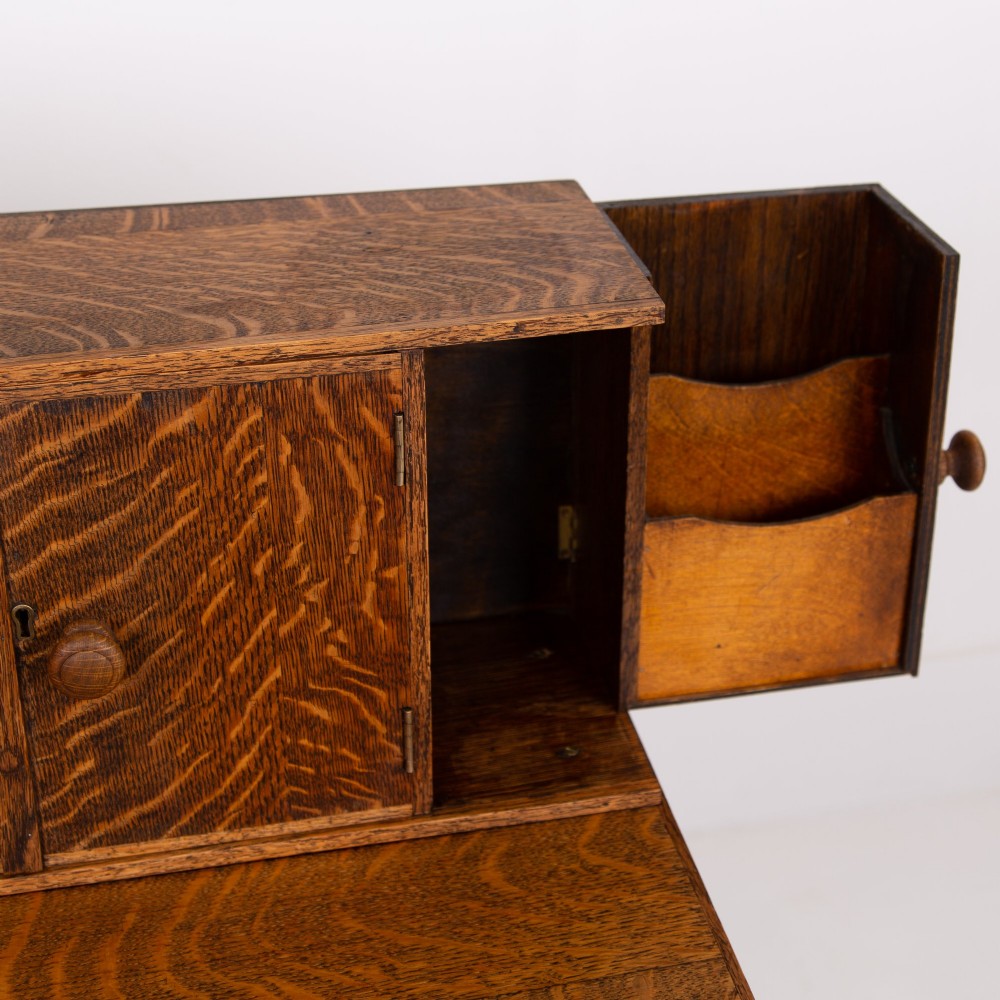 A 1930s warm brown oak writing desk featuring a top compartment with cupboard doors, side fold-out sections, and a single drawer on square legs. View IV