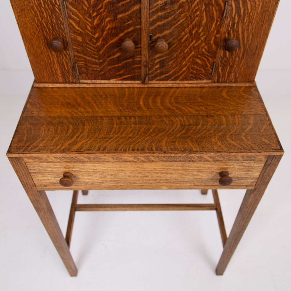 A 1930s warm brown oak writing desk featuring a top compartment with cupboard doors, side fold-out sections, and a single drawer on square legs. View VI