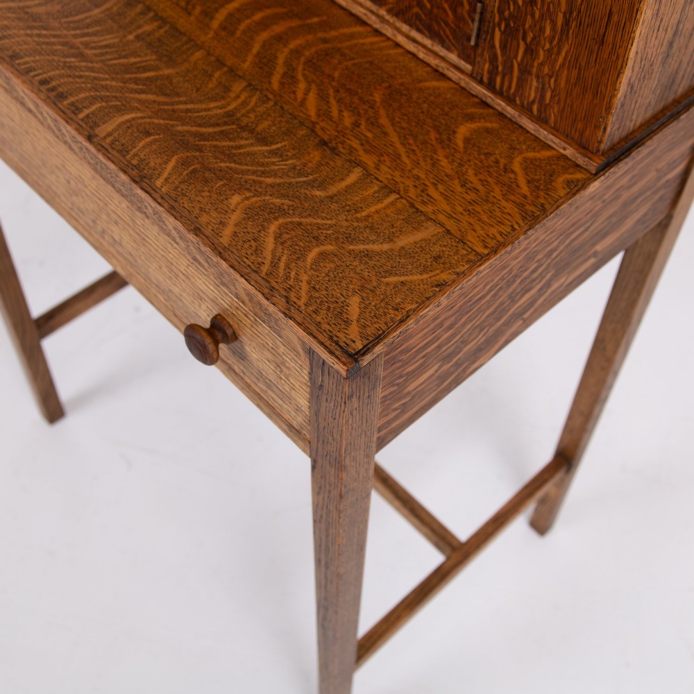 A 1930s warm brown oak writing desk featuring a top compartment with cupboard doors, side fold-out sections, and a single drawer on square legs. View VII