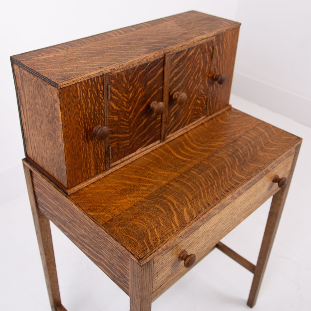 A 1930s warm brown oak writing desk featuring a top compartment with cupboard doors, side fold-out sections, and a single drawer on square legs. View IX