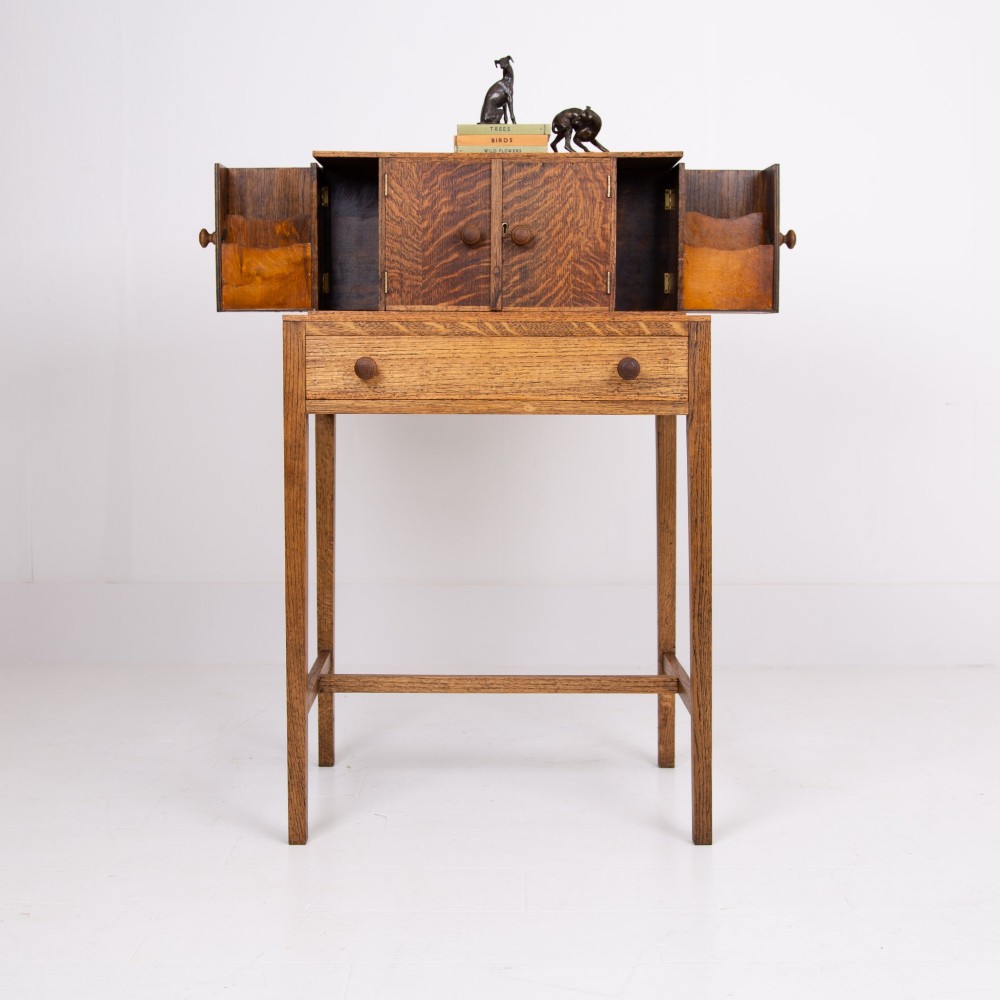 A 1930s warm brown oak writing desk featuring a top compartment with cupboard doors, side fold-out sections, and a single drawer on square legs. View XII