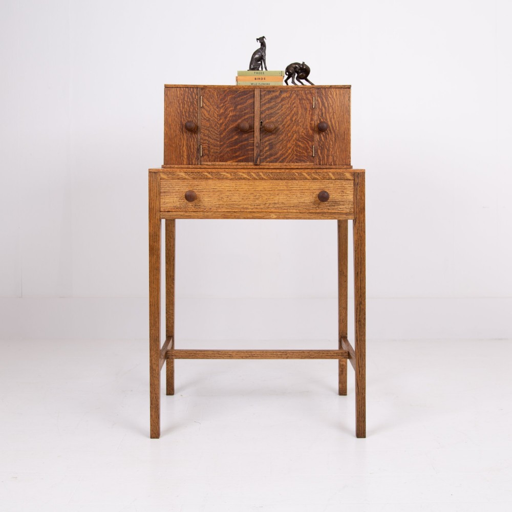 A 1930s warm brown oak writing desk featuring a top compartment with cupboard doors, side fold-out sections, and a single drawer on square legs. View XIII