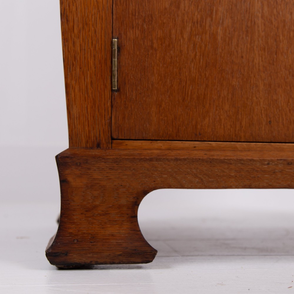 A 1930s Art Deco medium brown oak tallboy cabinet featuring two upper drawers with carved wooden handles and a double-door cupboard below. View III