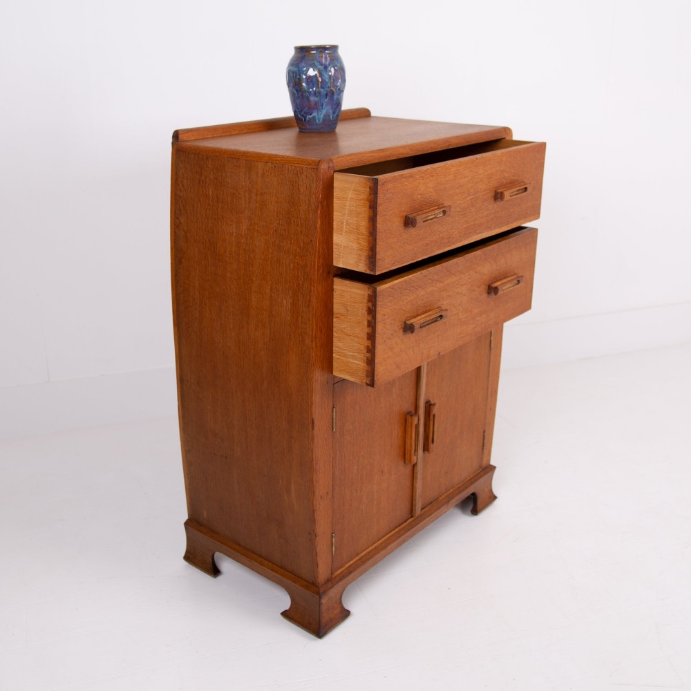 A 1930s Art Deco medium brown oak tallboy cabinet featuring two upper drawers with carved wooden handles and a double-door cupboard below. View IV