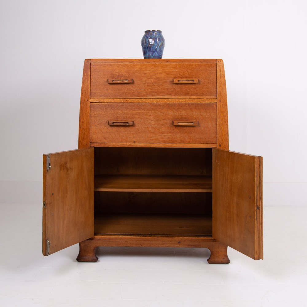 A 1930s Art Deco medium brown oak tallboy cabinet featuring two upper drawers with carved wooden handles and a double-door cupboard below. View V