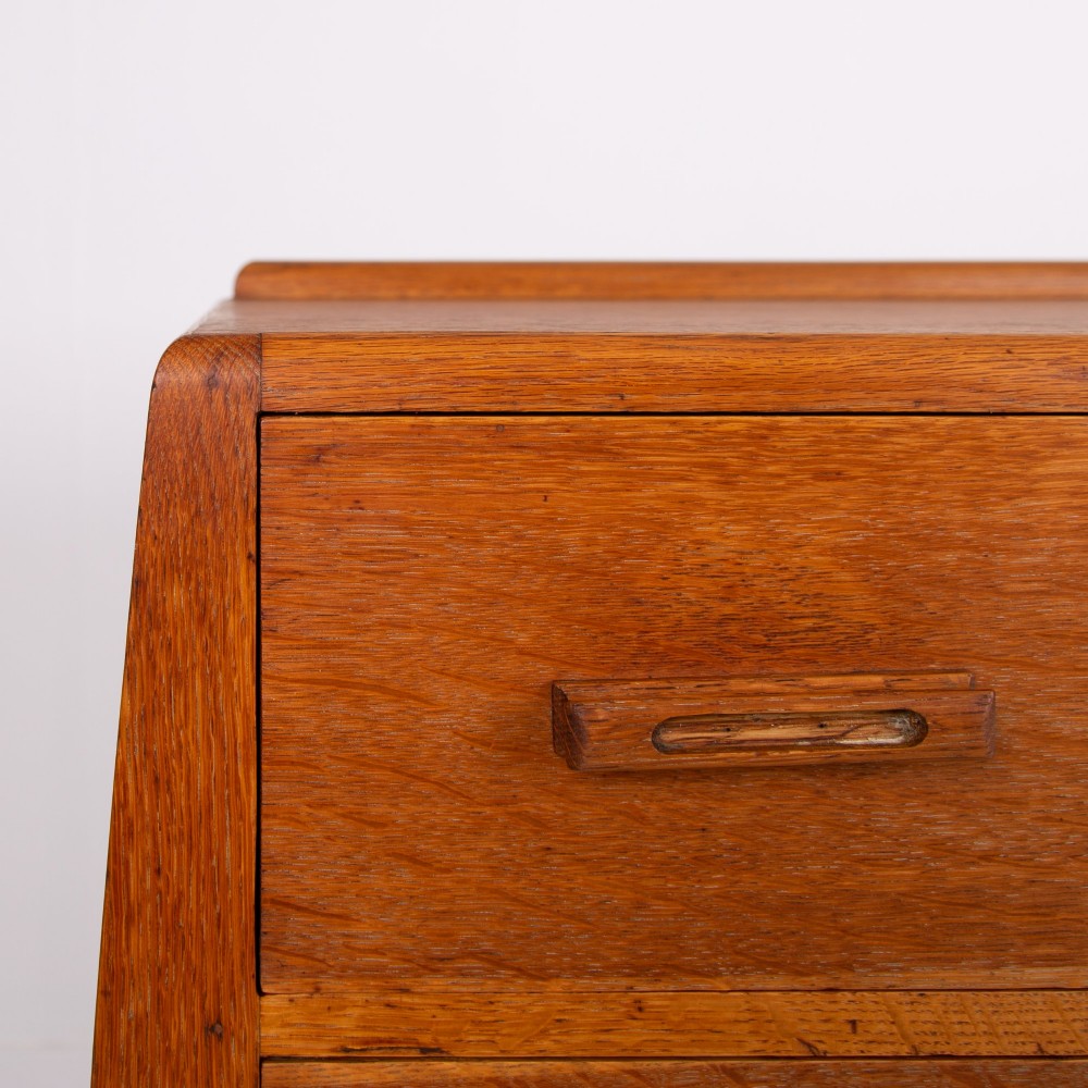 A 1930s Art Deco medium brown oak tallboy cabinet featuring two upper drawers with carved wooden handles and a double-door cupboard below. View VI