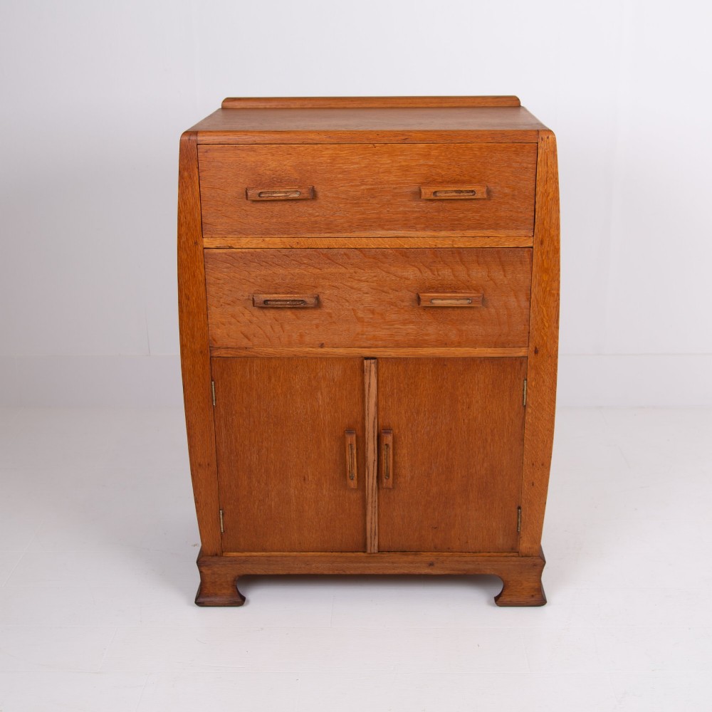 A 1930s Art Deco medium brown oak tallboy cabinet featuring two upper drawers with carved wooden handles and a double-door cupboard below. View IX