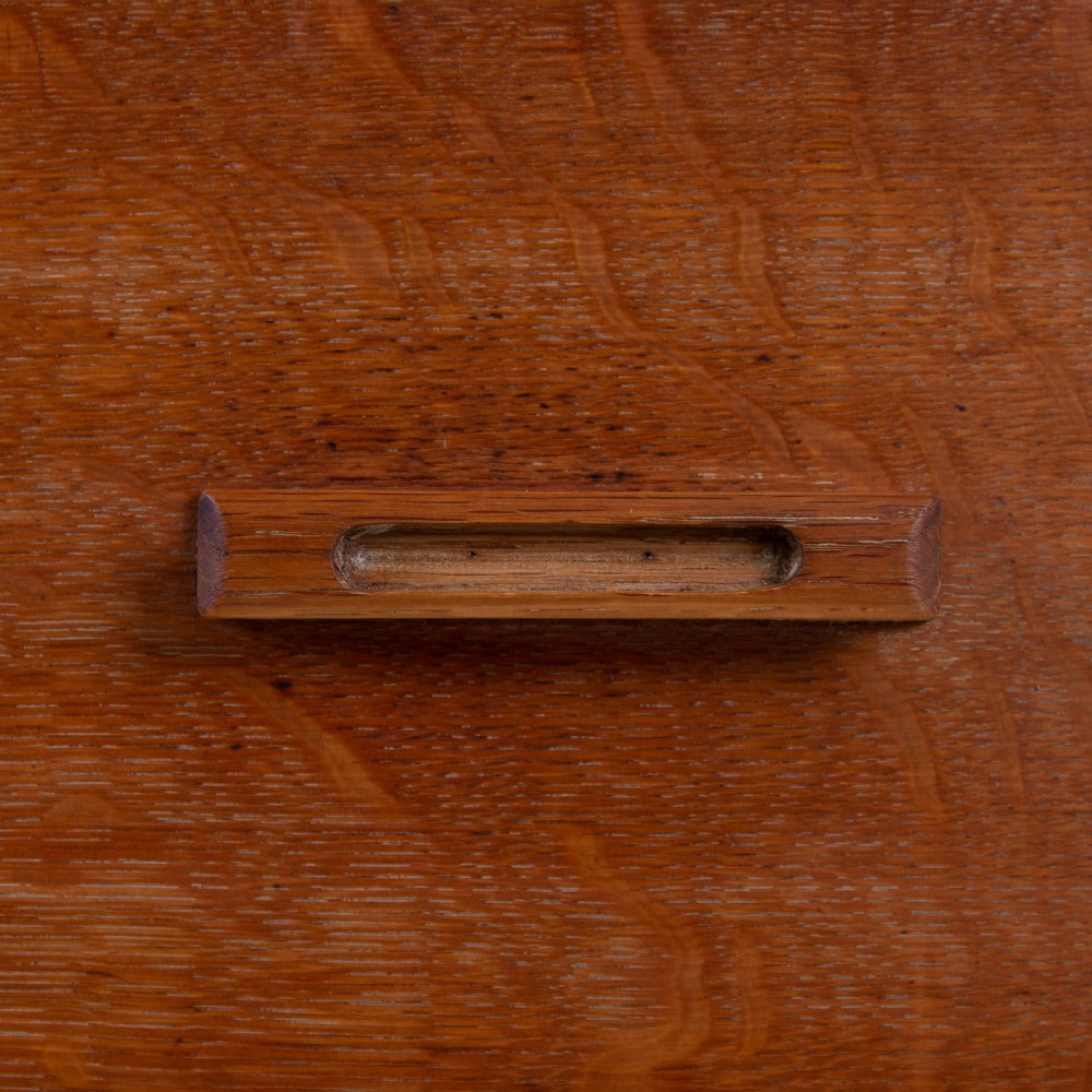 A 1930s Art Deco medium brown oak tallboy cabinet featuring two upper drawers with carved wooden handles and a double-door cupboard below. View X