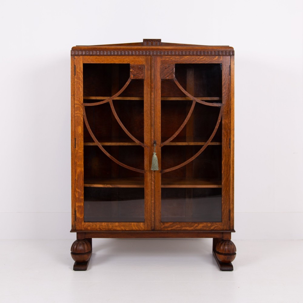 An Art Deco medium oak glazed bookcase featuring twin doors with decorative geometric wooden glazing bars and squat turned feet. View II
