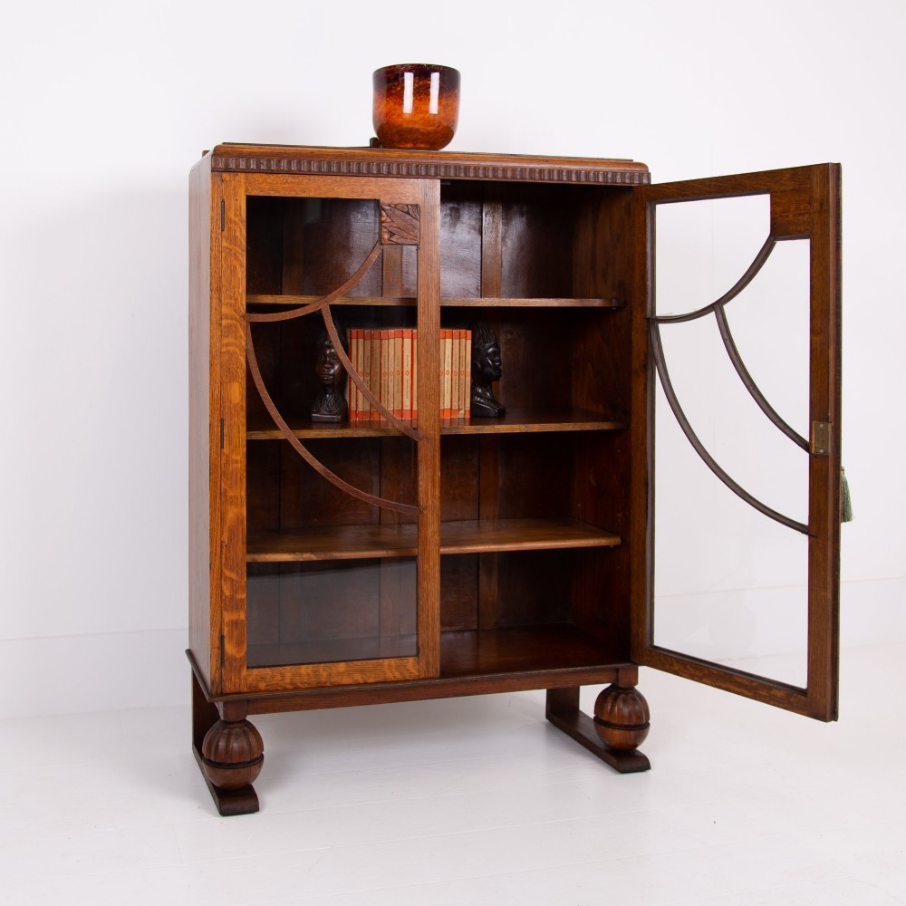 An Art Deco medium oak glazed bookcase featuring twin doors with decorative geometric wooden glazing bars and squat turned feet. View IV