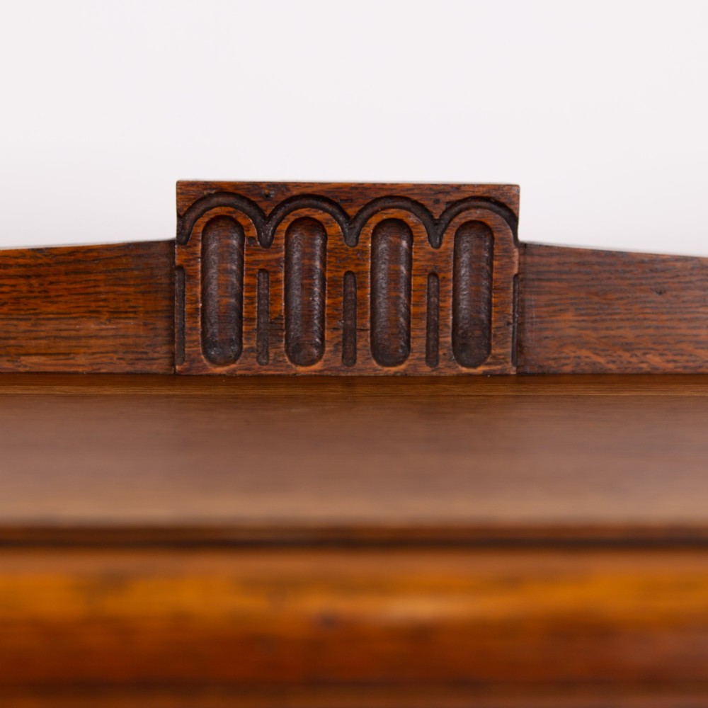 An Art Deco medium oak glazed bookcase featuring twin doors with decorative geometric wooden glazing bars and squat turned feet. View VI