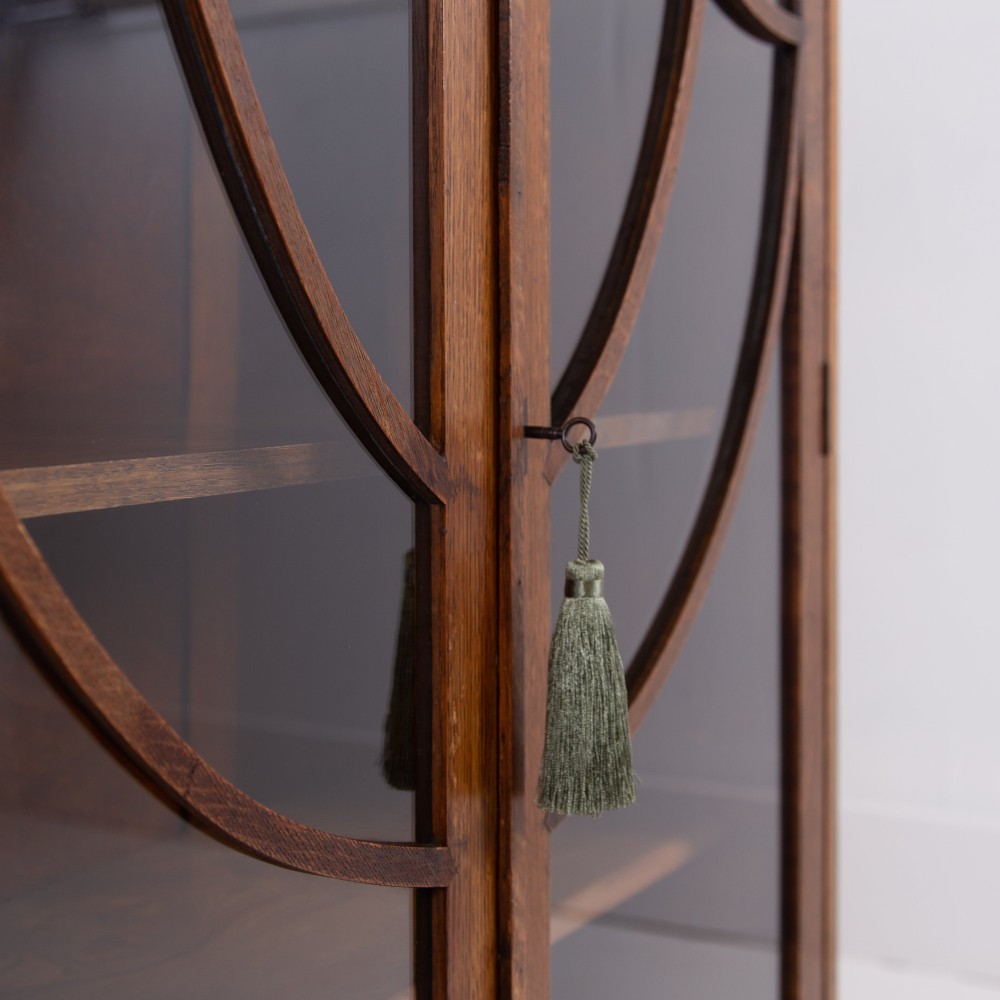 An Art Deco medium oak glazed bookcase featuring twin doors with decorative geometric wooden glazing bars and squat turned feet. View VII