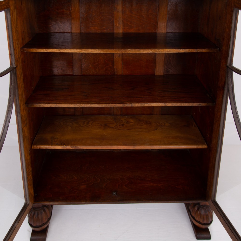 An Art Deco medium oak glazed bookcase featuring twin doors with decorative geometric wooden glazing bars and squat turned feet. View XII