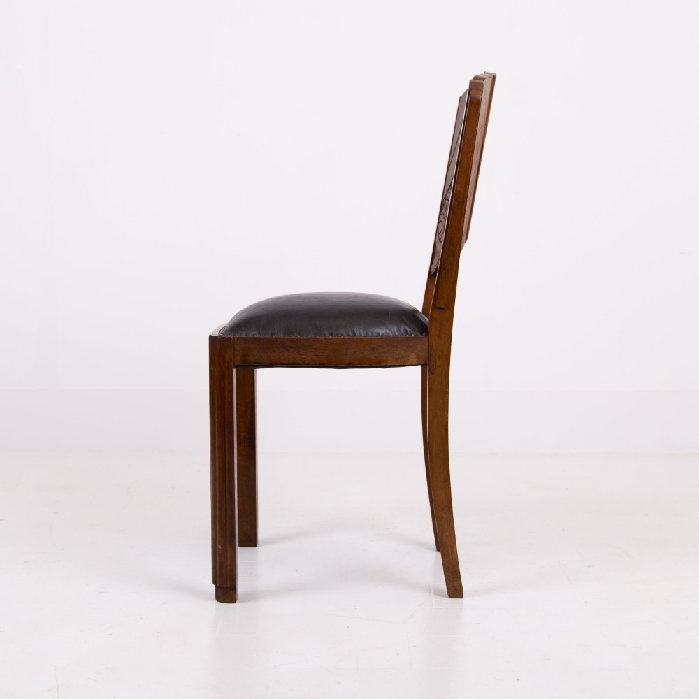 A set of four dark walnut dining chairs featuring carved sunburst motifs on the backs and dark leather upholstered seats. View IV