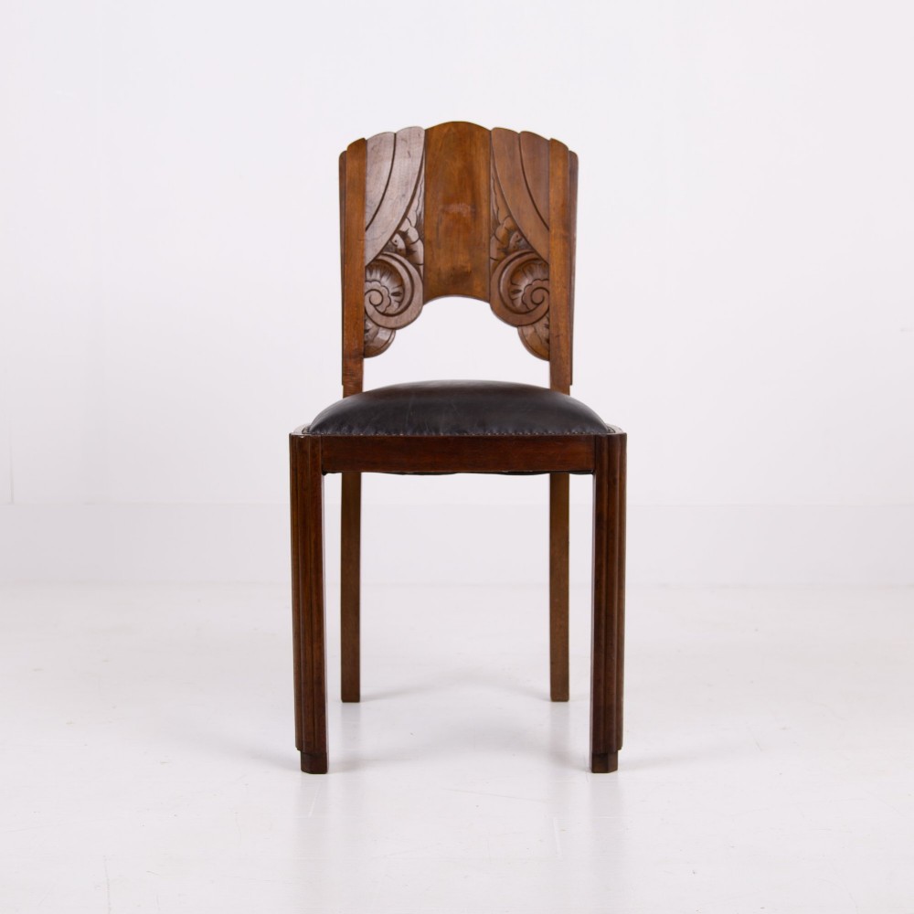 A set of four dark walnut dining chairs featuring carved sunburst motifs on the backs and dark leather upholstered seats. View V