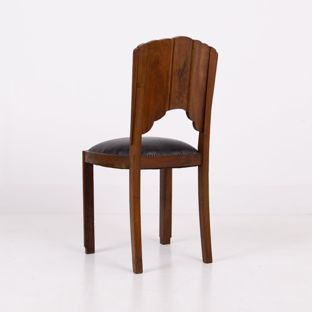 A set of four dark walnut dining chairs featuring carved sunburst motifs on the backs and dark leather upholstered seats. View VI