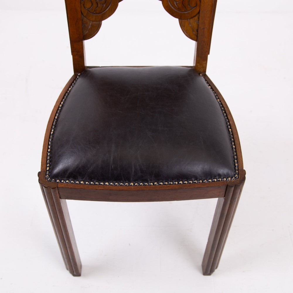 A set of four dark walnut dining chairs featuring carved sunburst motifs on the backs and dark leather upholstered seats. View VIII