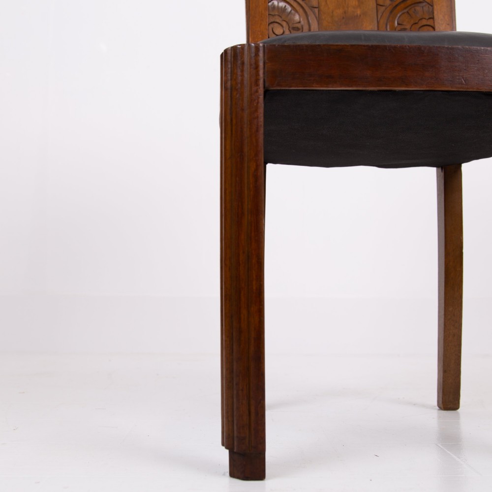 A set of four dark walnut dining chairs featuring carved sunburst motifs on the backs and dark leather upholstered seats. View X