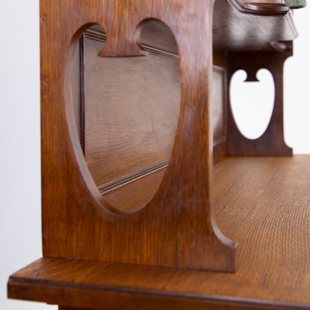 An Arts and Crafts oak cabinet dresser featuring an upper shelf unit with a central stained glass cabinet door, side heart cutouts, lower cupboards, a single drawer, and an open side niche. View VI