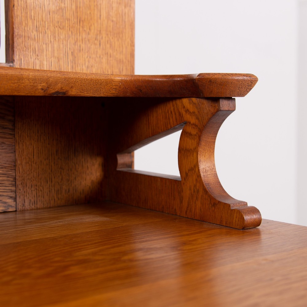 An Arts and Crafts oak dressing chest featuring a superstructure with a central mirror, inlaid side panels, and small jewellery drawers above a chest of drawers. View XV