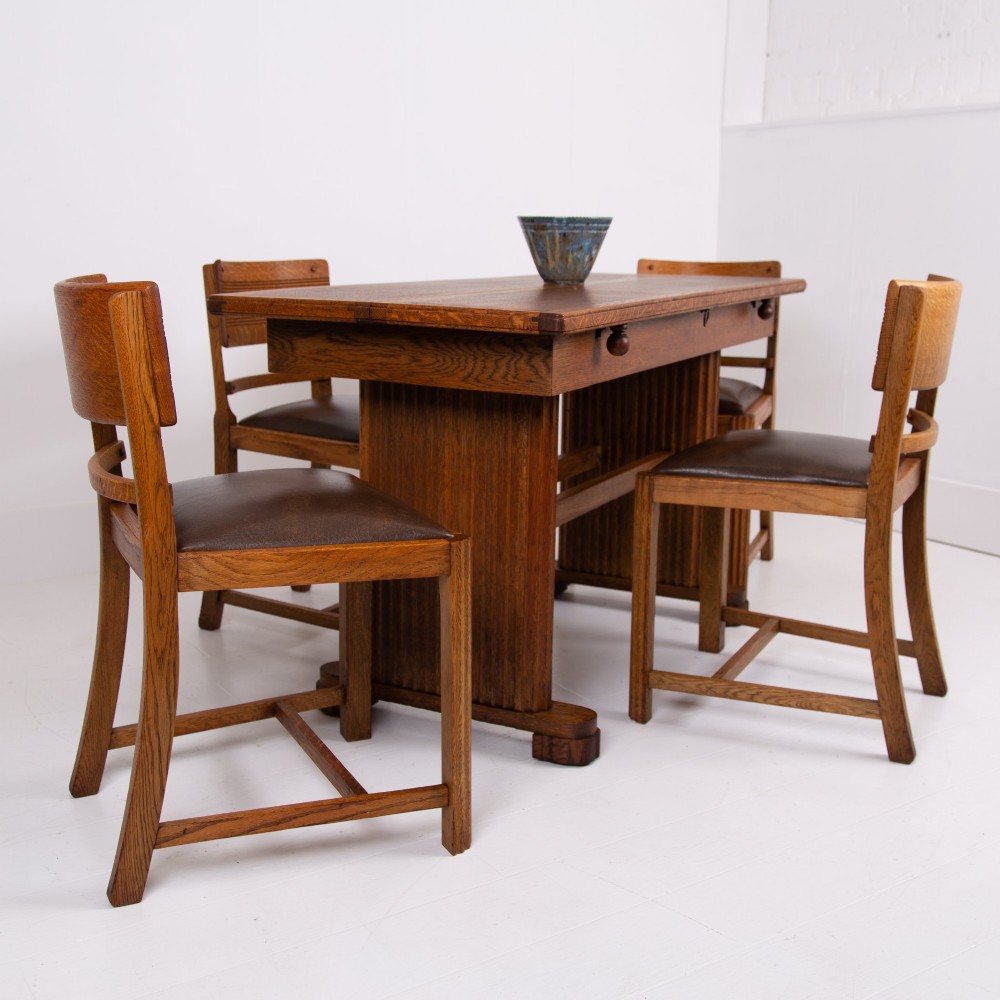 An Art Deco medium oak dining set comprising a rectangular pedestal table and four matching chairs with brown leather seats. View XV