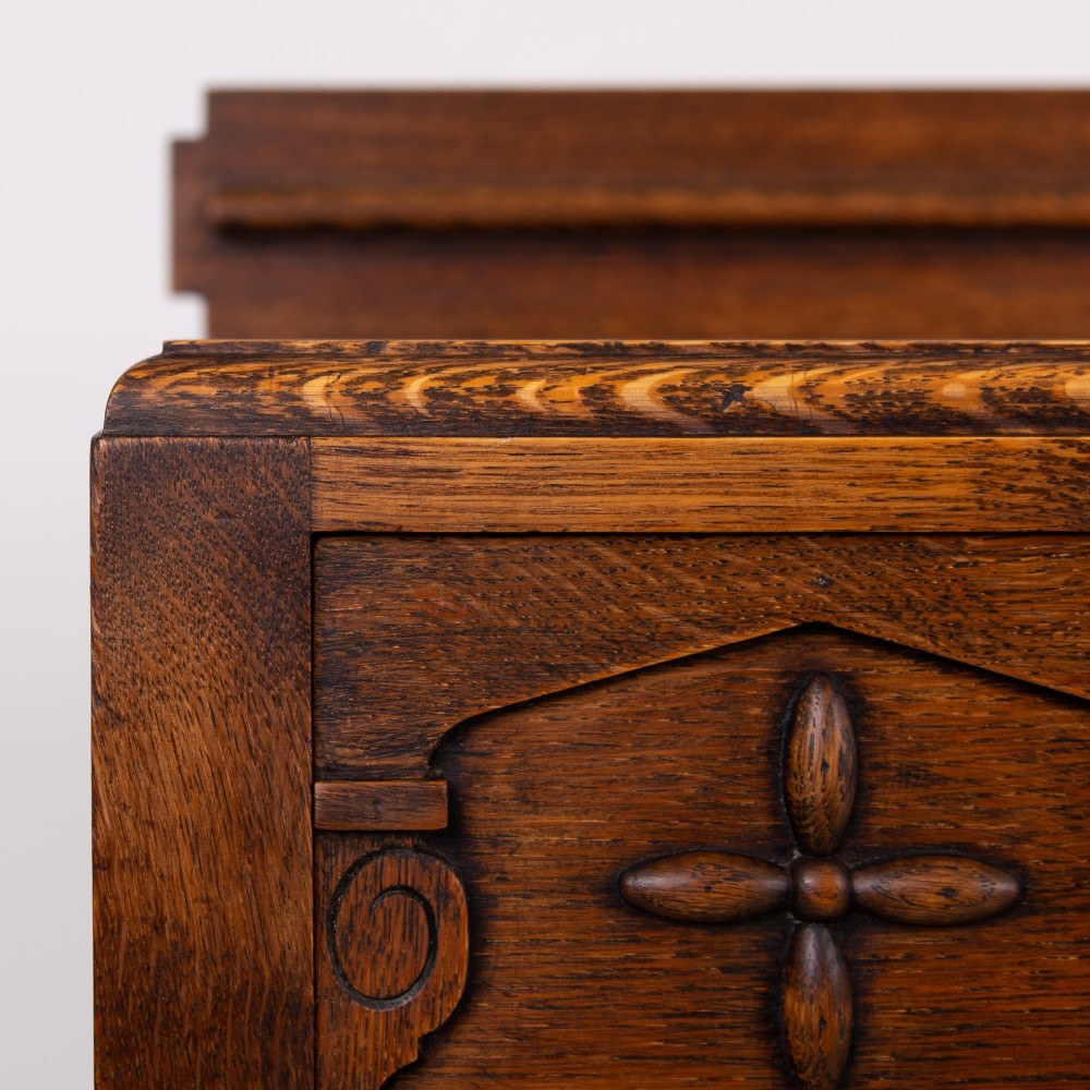 A 1930s warm brown oak sideboard featuring two carved top drawers above a double-door cupboard, supported by block legs and a low stretcher base. View IV