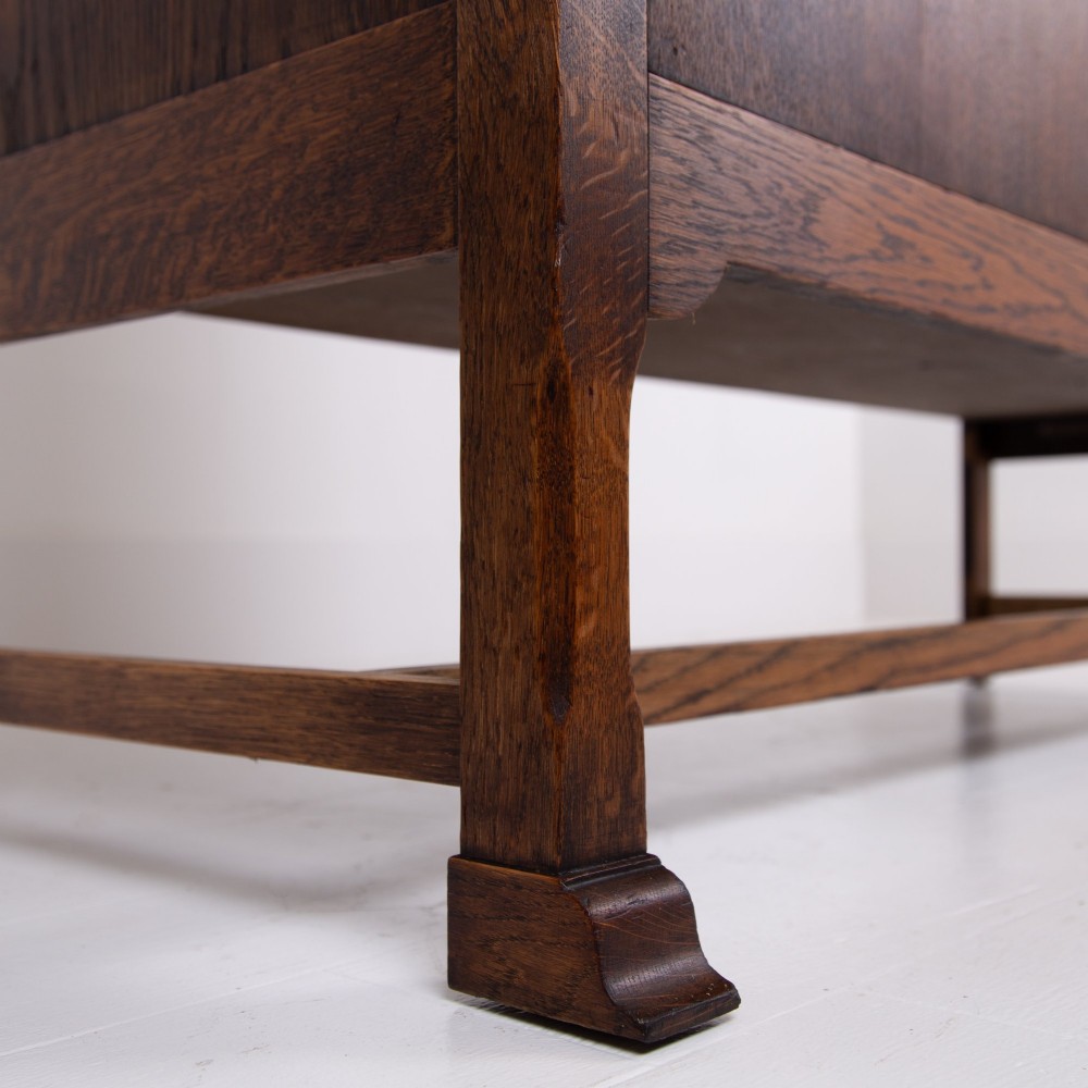 A 1930s warm brown oak sideboard featuring two carved top drawers above a double-door cupboard, supported by block legs and a low stretcher base. View V