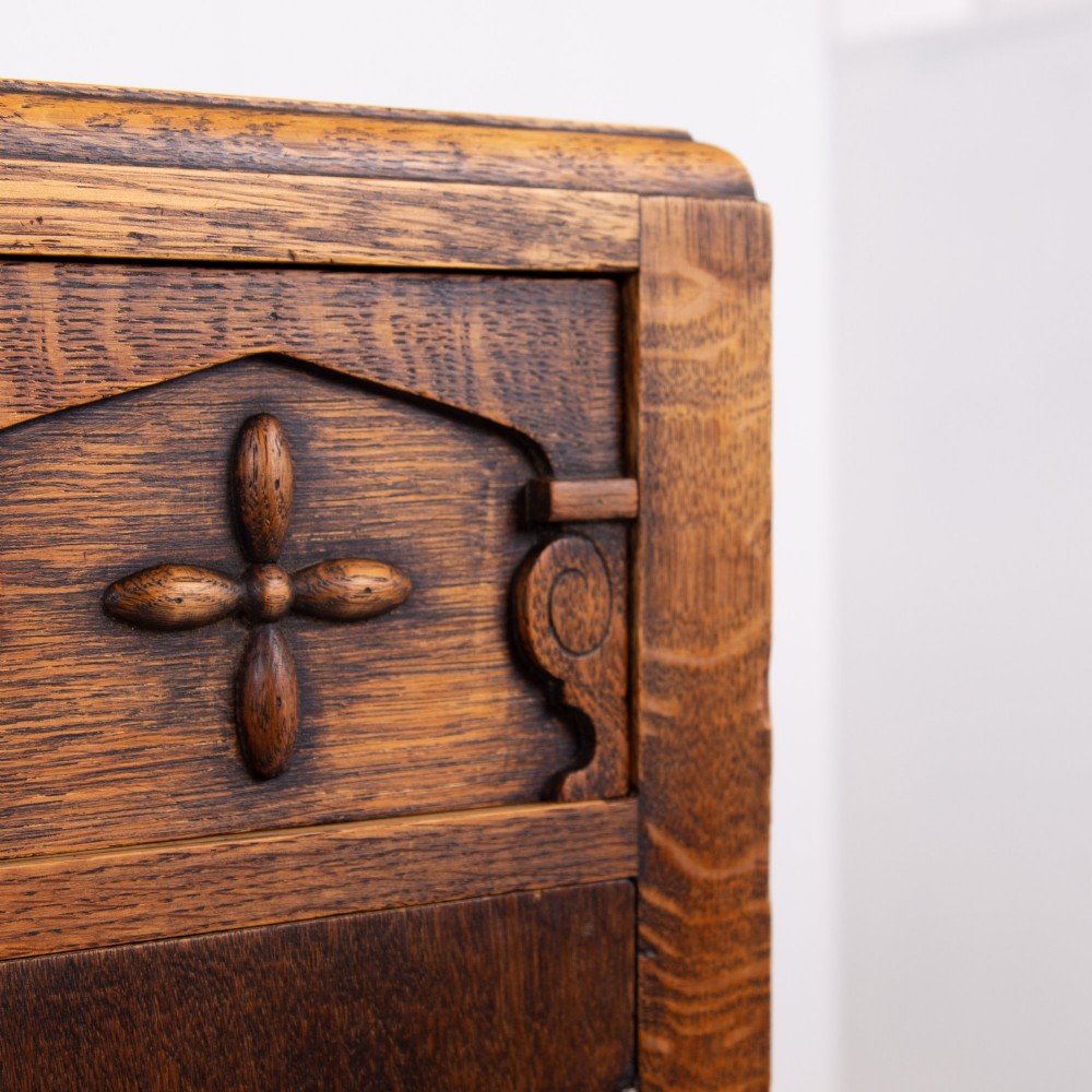 A 1930s warm brown oak sideboard featuring two carved top drawers above a double-door cupboard, supported by block legs and a low stretcher base. View XIII