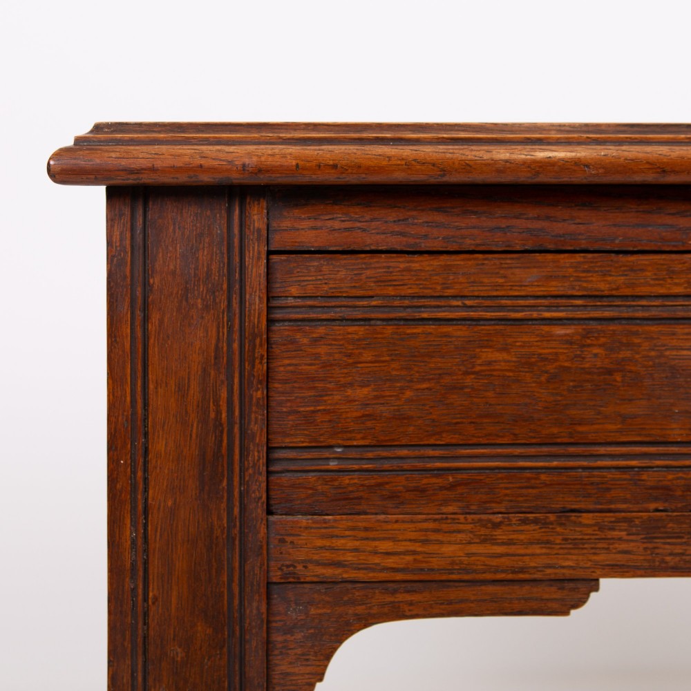 A Victorian solid oak writing desk featuring two drawers with brass drop handles and supported by four turned legs. View III