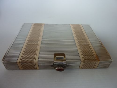 fig 1. An Art Deco rectangular vanity case with engine-turned geometric silver and gold stripes and a central cabochon clasp.