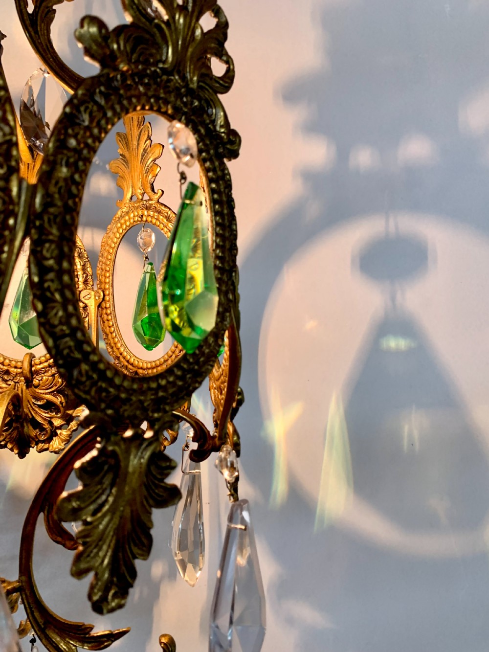 An ornate gilded bronze Florentine pendant light featuring scrolling leaf motifs, oval frame inserts enclosing faceted green crystals, and hanging clear glass prisms. View III