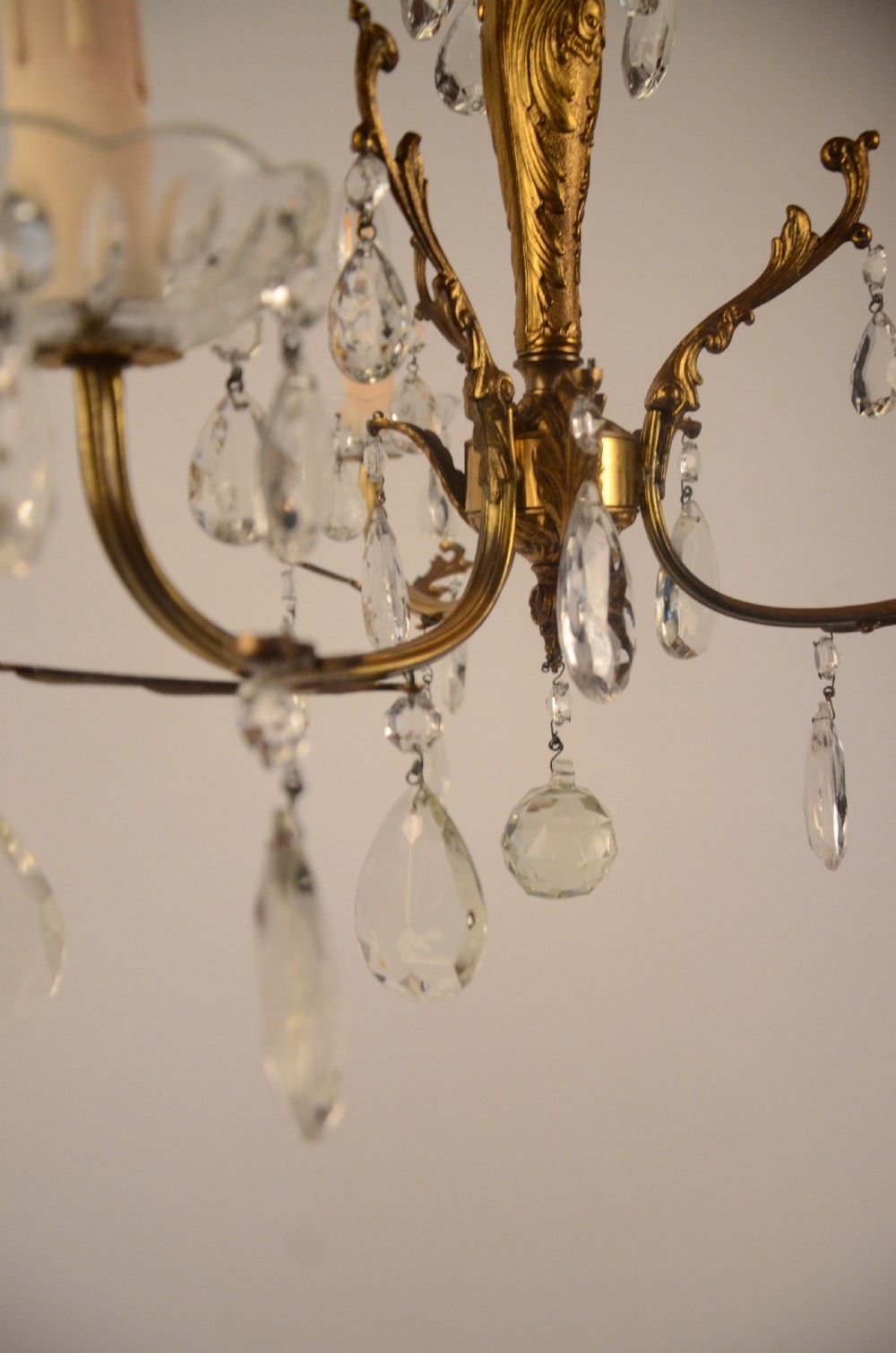 A three-arm gilt brass Italian chandelier decorated with hanging glass teardrop prisms and candle-effect light fittings. View VIII