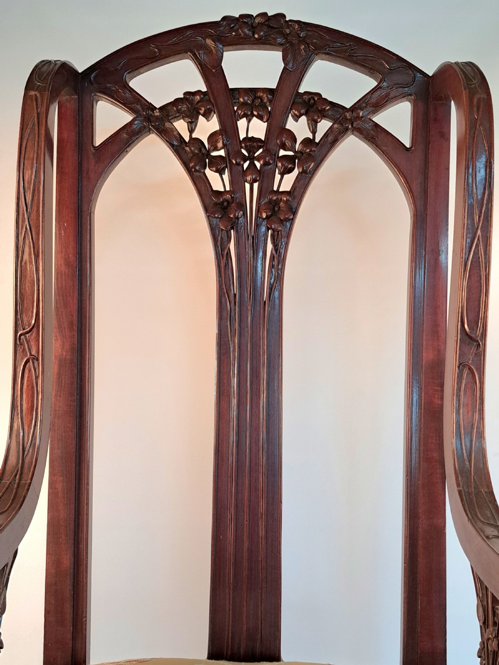 An Art Nouveau carved dark wood armchair featuring organic plant-inspired carved backrest detailing and a light green upholstered seat. View VI