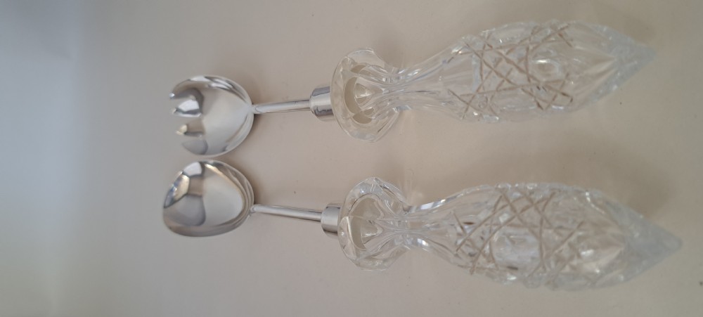 A circular cut crystal salad bowl with a silver rim, accompanied by a pair of silver and crystal-handled salad servers. View XV