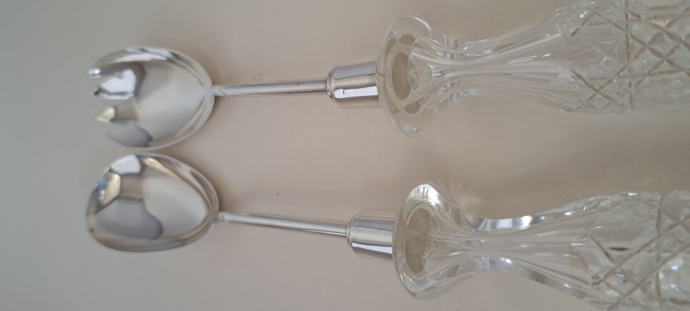A circular cut crystal salad bowl with a silver rim, accompanied by a pair of silver and crystal-handled salad servers. View XVI