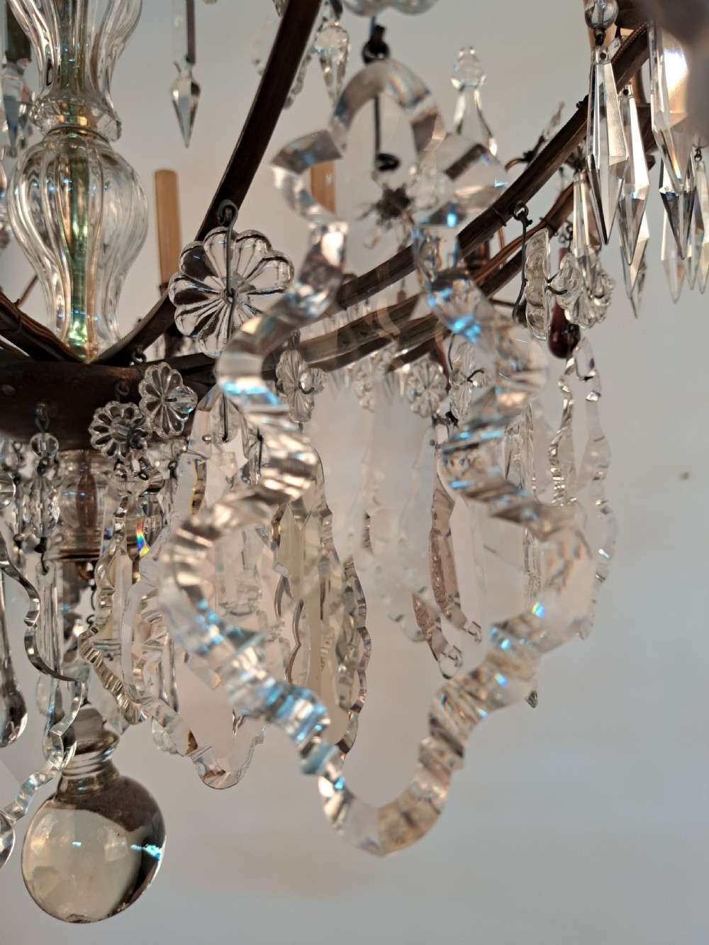 A multi-arm French crystal chandelier with candle-style light sockets, clear faceted glass prisms, and purple teardrop pendants on a dark wrought iron frame. View XII