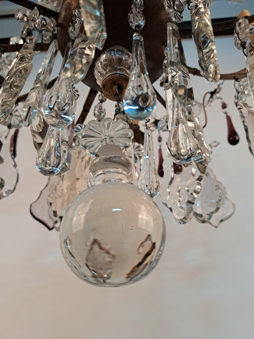A multi-arm French crystal chandelier with candle-style light sockets, clear faceted glass prisms, and purple teardrop pendants on a dark wrought iron frame. View XIII