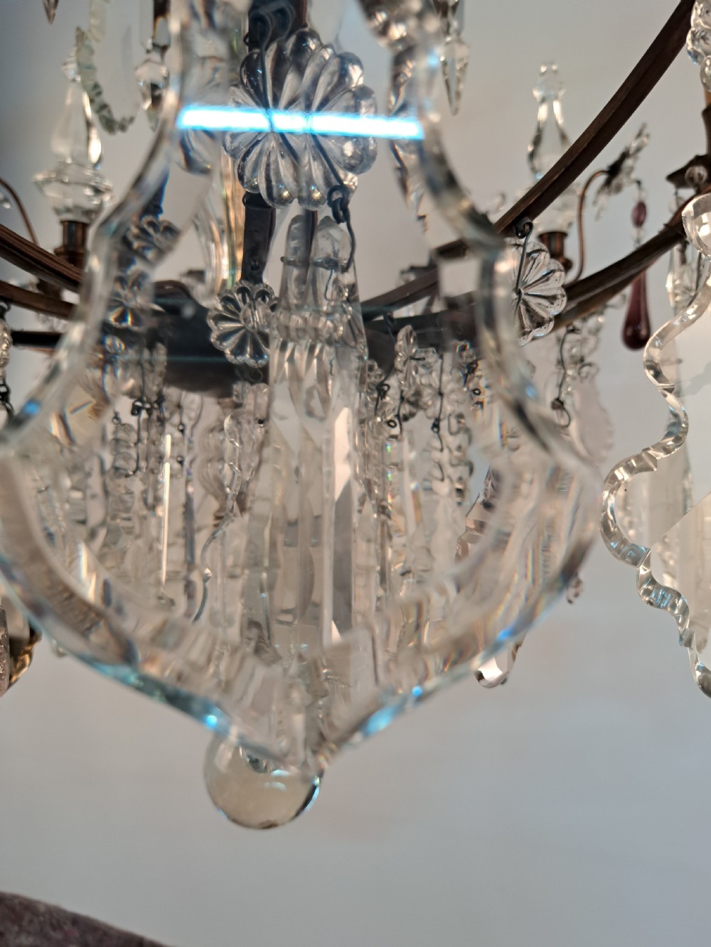 A multi-arm French crystal chandelier with candle-style light sockets, clear faceted glass prisms, and purple teardrop pendants on a dark wrought iron frame. View XIV