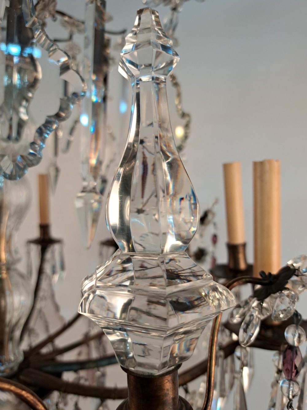 A multi-arm French crystal chandelier with candle-style light sockets, clear faceted glass prisms, and purple teardrop pendants on a dark wrought iron frame. View XV