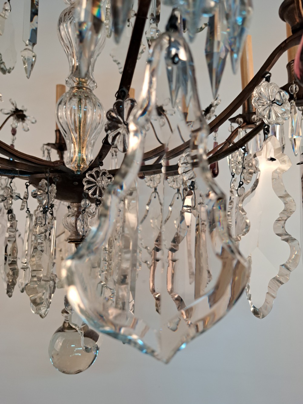 A multi-arm French crystal chandelier with candle-style light sockets, clear faceted glass prisms, and purple teardrop pendants on a dark wrought iron frame. View XVI