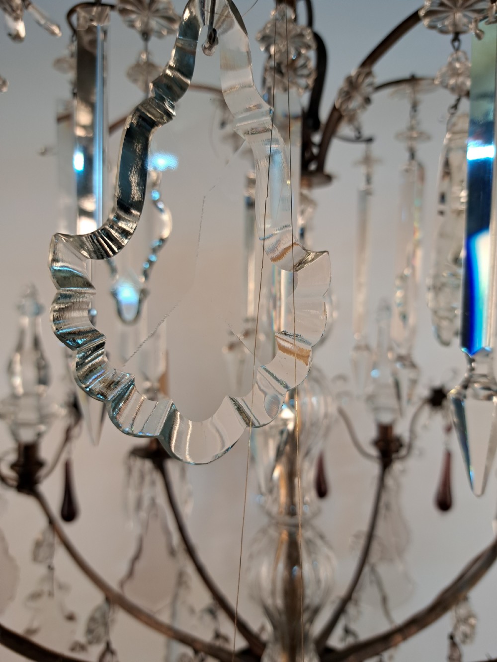 A multi-arm French crystal chandelier with candle-style light sockets, clear faceted glass prisms, and purple teardrop pendants on a dark wrought iron frame. View XX