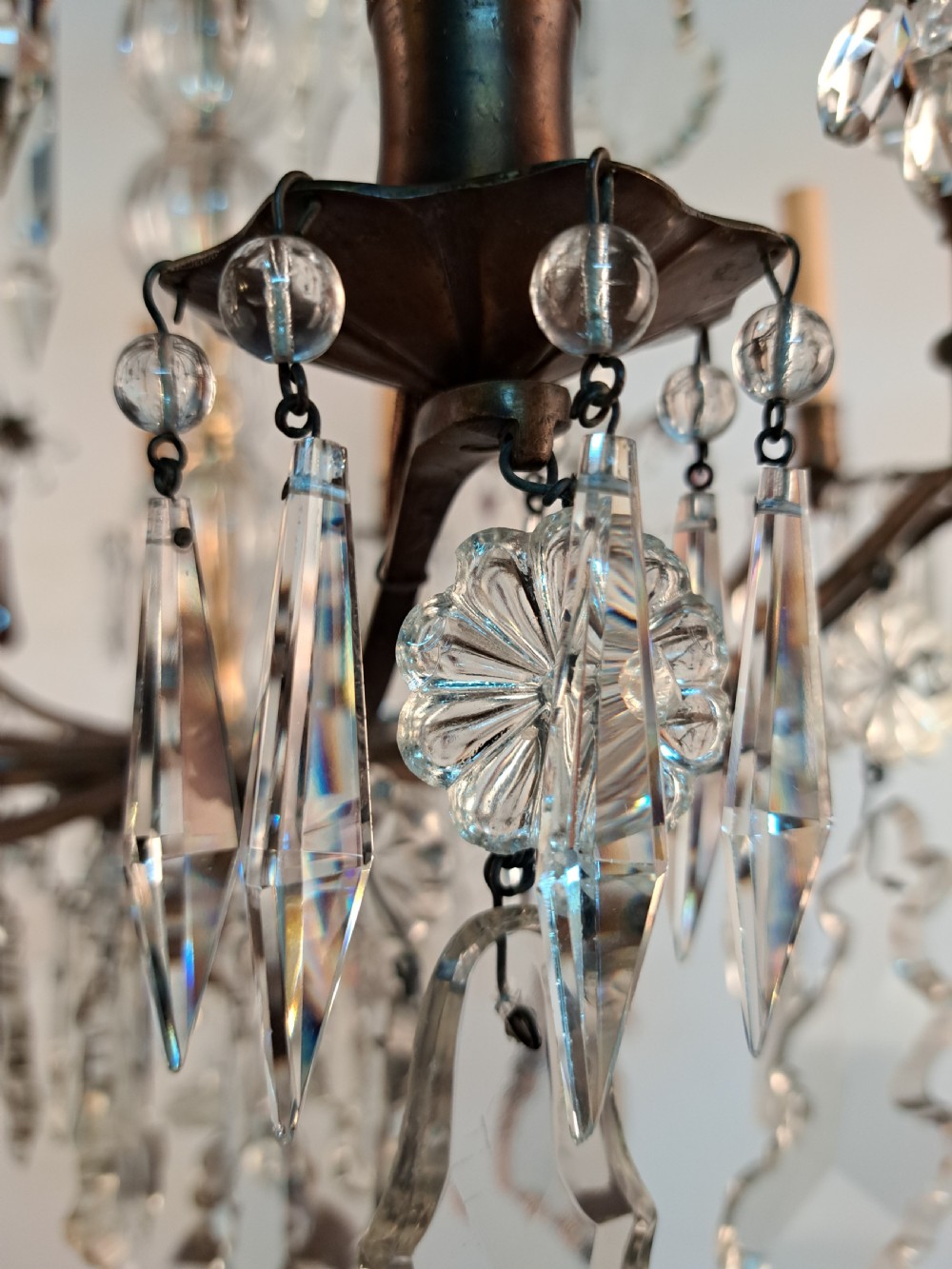 A multi-arm French crystal chandelier with candle-style light sockets, clear faceted glass prisms, and purple teardrop pendants on a dark wrought iron frame. View XXI