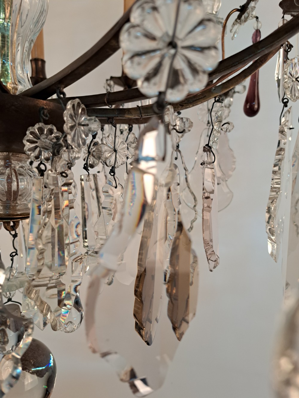 A multi-arm French crystal chandelier with candle-style light sockets, clear faceted glass prisms, and purple teardrop pendants on a dark wrought iron frame. View XXII