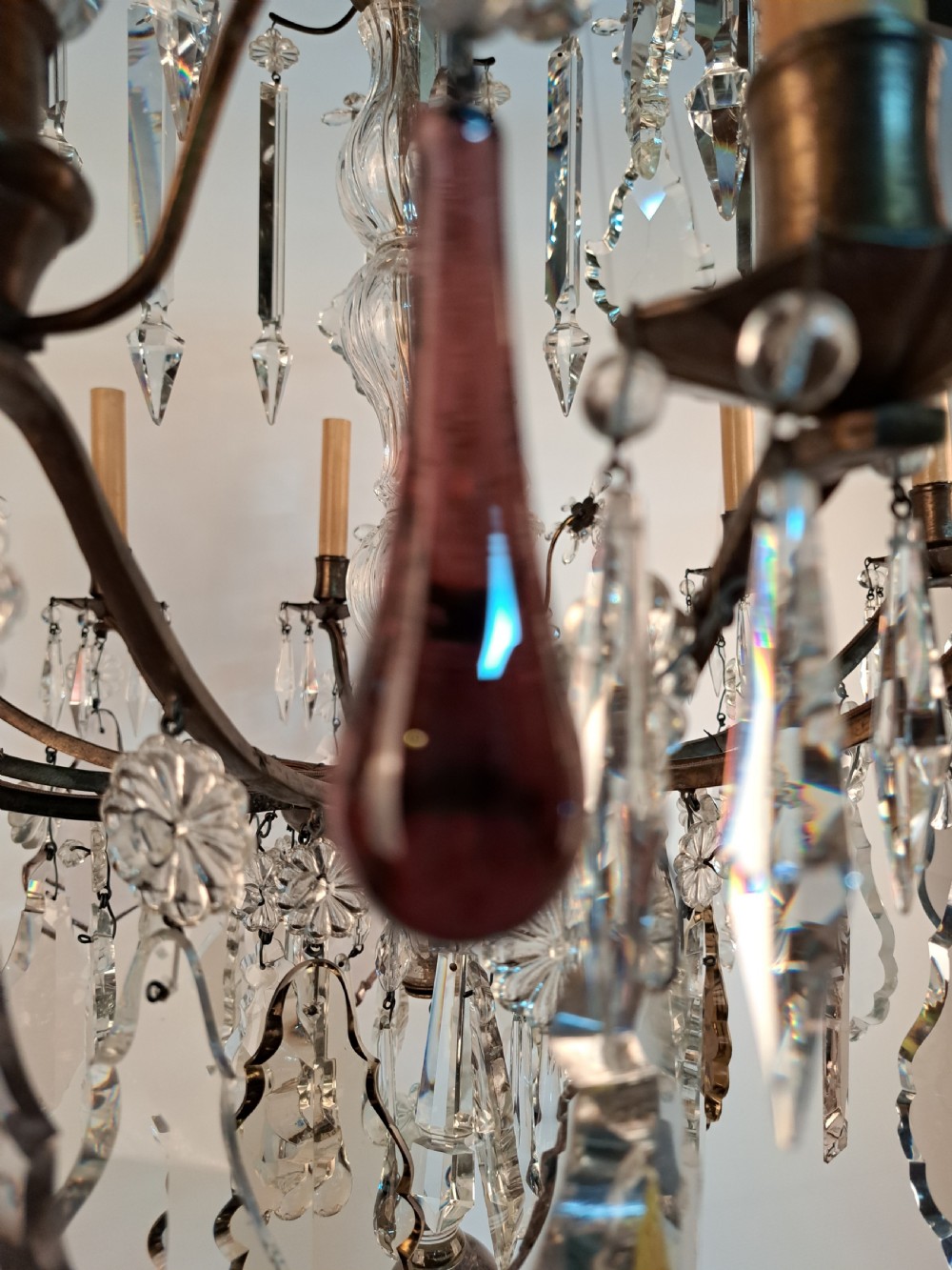 A multi-arm French crystal chandelier with candle-style light sockets, clear faceted glass prisms, and purple teardrop pendants on a dark wrought iron frame. View XXIV